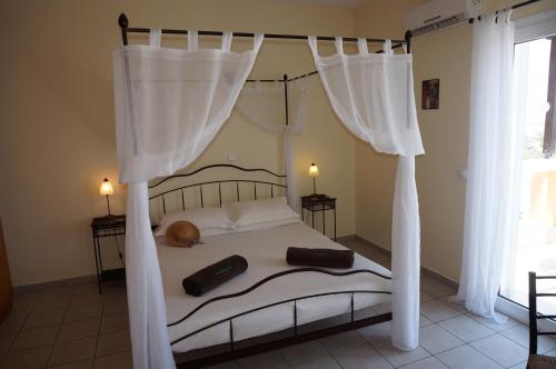 1 dormitorio con cama con dosel y 2 mandos a distancia en Rhodes Demetrius Luxury Private Villa, en Kalathos