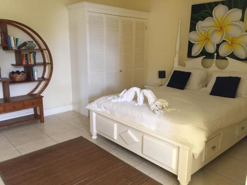 a white bed in a room with a mirror at South Sea House in Cap Estate