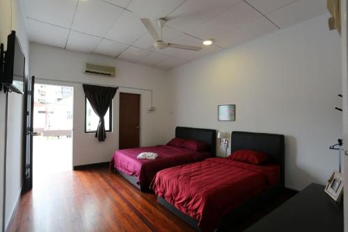 a bedroom with two beds with red sheets at Bee's Homestay in George Town