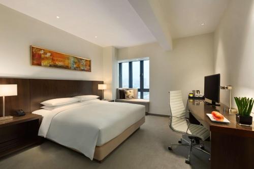 a bedroom with a white bed and a desk and a chair at Hyatt Place Shenzhen Dongmen in Shenzhen