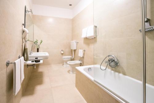 a bathroom with a tub and a toilet and a sink at Hotel Europa in Ferrara