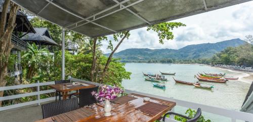 a balcony with a table and chairs and a river with boats at Kamala Beach Estate Resort - SHA Extra Plus in Kamala Beach