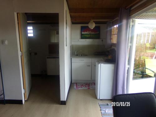 a small kitchen with white cabinets and a door open at Les Aubepines in La Plaine des Palmistes