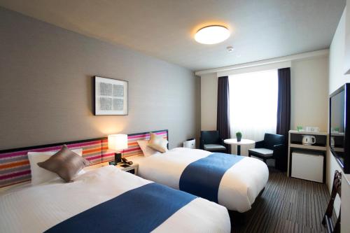 a hotel room with two beds and a television at Hotel La'gent Plaza Hakodate Hokuto in Hokuto