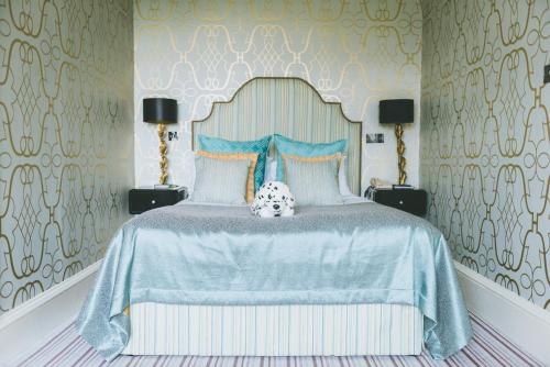 a bedroom with a bed with a blue bedspread at The Coed-Y-Mwstwr Hotel in Bridgend