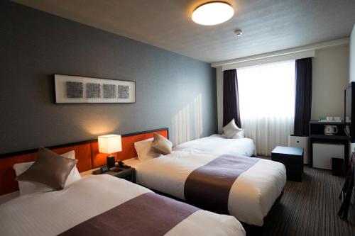 a hotel room with two beds and a window at Hotel La'gent Plaza Hakodate Hokuto in Hokuto