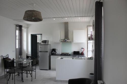 une cuisine et une salle à manger avec une table et un réfrigérateur dans l'établissement Charmante maison charentaise 
