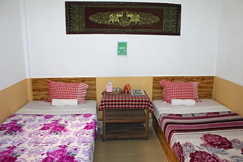 a room with two beds and a table in it at Garden Guesthouse in Kampong Chhnang