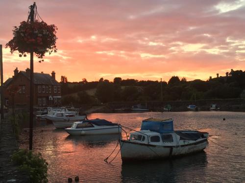 a group of boats sitting in the water at sunset at Blue Water Breaks - Dawlish Warren in Dawlish