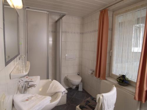 a white bathroom with a sink and a toilet at Pension Gastreich in Lennestadt