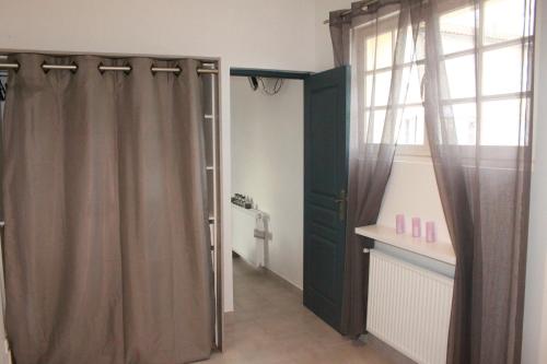 La salle de bains est pourvue d'une porte verte et d'une fenêtre. dans l'établissement Charmante maison charentaise 