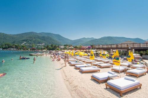 a beach with chairs and umbrellas and people in the water at Apartmani Sindik in Tivat