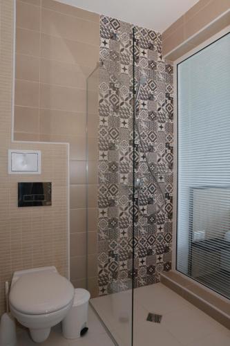 a bathroom with a toilet and a glass shower at St. Stefan Villas & Hotel in Sozopol