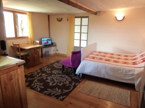 a bedroom with a bed and a table and a tv at The Studio in Saint-Ségal
