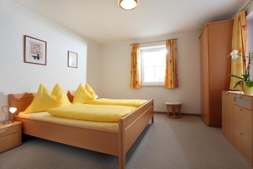 a bedroom with a bed with yellow sheets and a window at Appartements Oberhauser in Westendorf