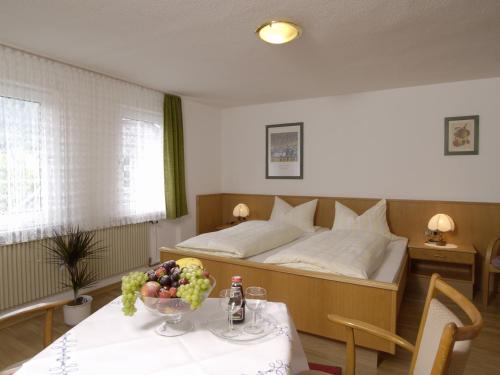 Un dormitorio con una cama y una mesa con un bol de fruta en Pension Gastreich en Lennestadt