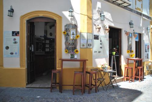 a building with tables and stools in a street at Pensión San Marcos in Arcos de la Frontera