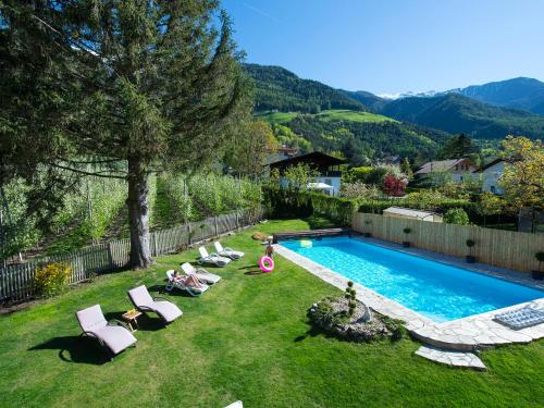 a backyard with a swimming pool and lounge chairs at Pension Lärchenhof in Naturno