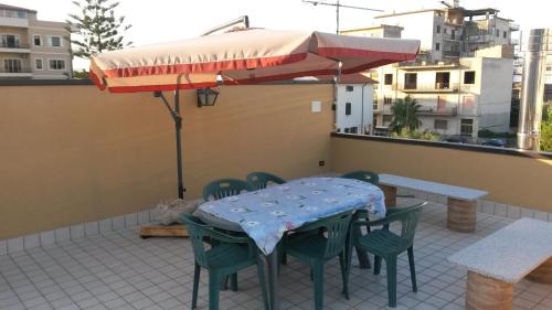 a table and chairs and an umbrella on a patio at Erasippe Residence in Locri