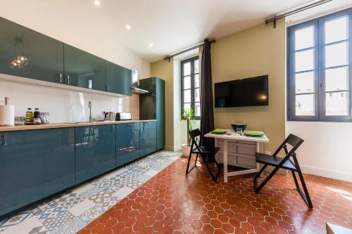 une cuisine avec des armoires vertes, une table et des chaises dans l'établissement Chez Nous - 7 Appartements sur le Vieux Port, à Marseille
