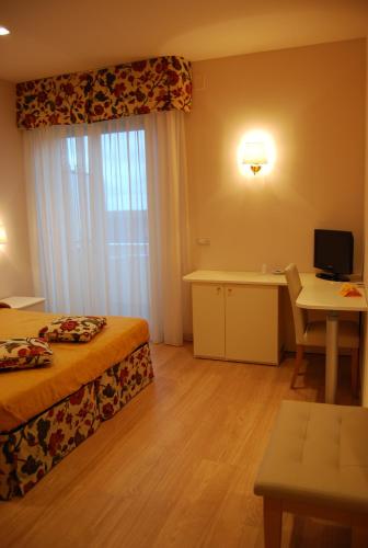 a hotel room with a bed and a desk and a window at Hotel Bahia in San Benedetto del Tronto