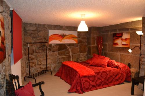 ゴウヴェイアにあるCasa d' Avo Elisaの赤いベッドと石の壁が備わるベッドルーム1室