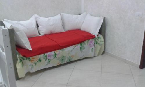ein kleines Bett mit Kissen und einer roten Decke in der Unterkunft Jardim Atlantico in Paripueira