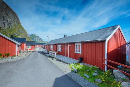 a row of red buildings with a mountain in the background at Eliassen Rorbuer in Reine