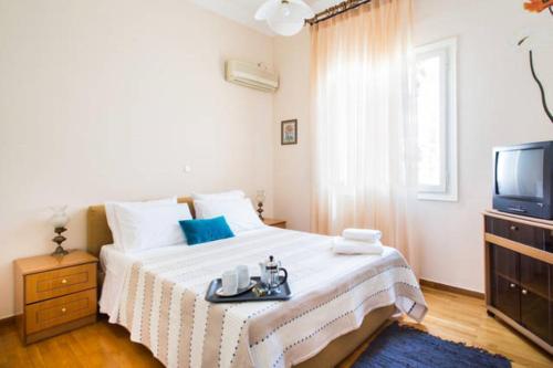 um quarto branco com uma cama e uma televisão em Large 3 bedroom Apt with Terrace em Atenas