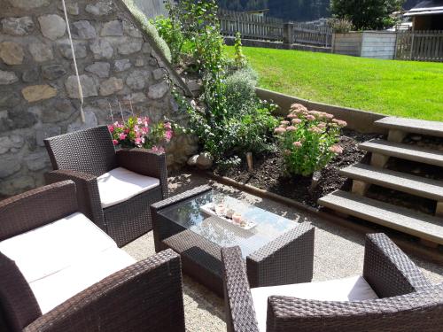 a patio with wicker chairs and a table in a yard at Haus Mattle in Pettneu am Arlberg