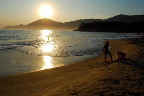 two people walking on the beach at sunset at Ciribaí Praia Hotel in Pauba