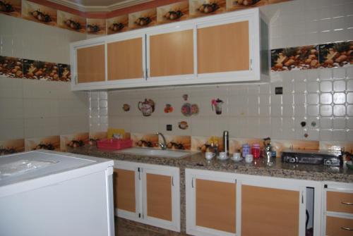 a kitchen with white cabinets and a sink at Résidence MARWA in Ouarzazate