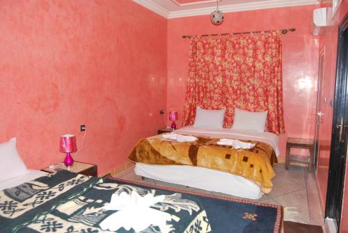 duas camas num quarto com paredes vermelhas em Résidence MARWA em Uarzazate