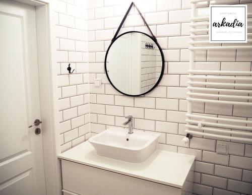 a white bathroom with a sink and a mirror at Arkadia Apartament nad samym morzem in Gdańsk
