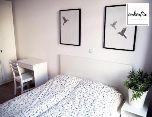 グダニスクにあるArkadia Apartament nad samym morzemのベッドルーム1室(ベッド1台、デスク付)、壁に鳥2羽が備わります。