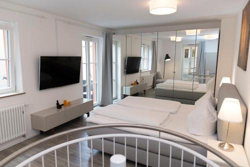 a white room with a bed and a television at Arnulfsplatz Aparts in Regensburg