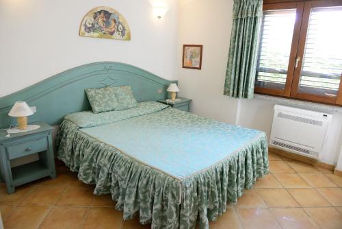 a bedroom with a bed and two tables and a window at Nuova Valmar Villa Condominio Rei Sole in Costa Rei