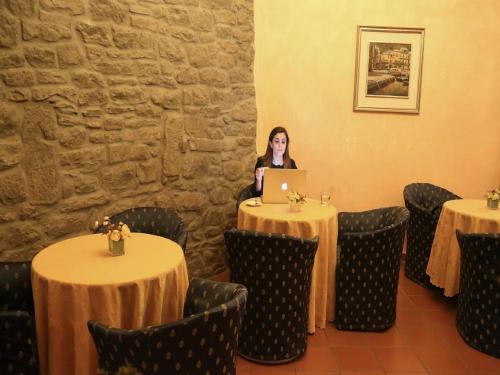 a woman sitting at a table with a laptop at Hotel Italia Cortona in Cortona