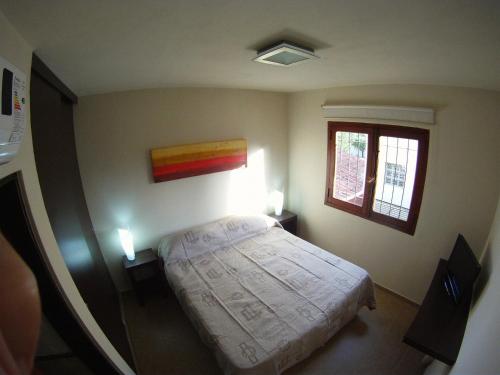 a small bedroom with a bed and two windows at Hotel Urbana in Córdoba