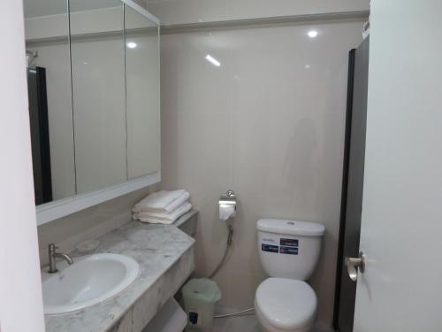 a bathroom with a sink and a toilet and a mirror at Sunshine Beach Condotel by Lux in Na Jomtien
