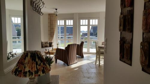 a living room with chairs and a table and windows at Landhaus am Binnensee in Fehmarn