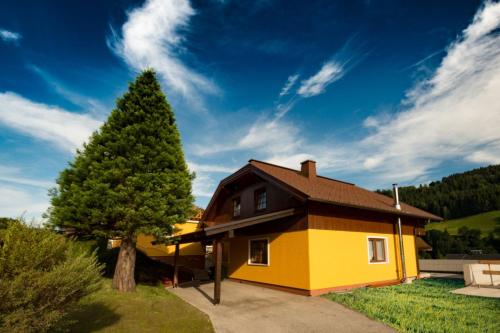 a yellow house with a tree in the yard at Sun Chalet in Schladming