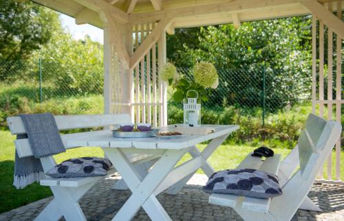a white picnic table with two chairs and a table with food at Apartamenty U Harrego I Przy Stawie Spa z klimatyzacją, balia, sauna, ogrodem i parkingiem in Kudowa-Zdrój