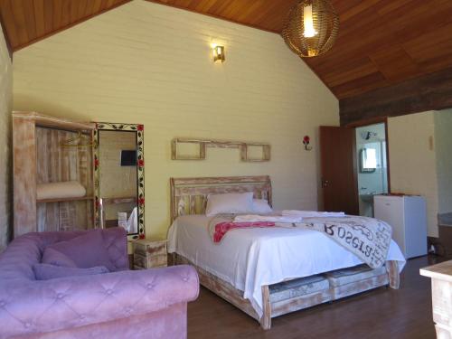 a bedroom with a large bed and a couch at Chalé da Serra in São João del Rei