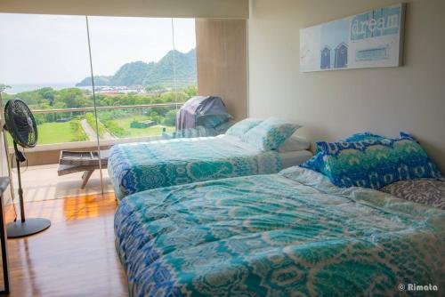 a bedroom with two beds and a large window at Luxury Beach Apartment Herradura Fishermen And Family in Herradura