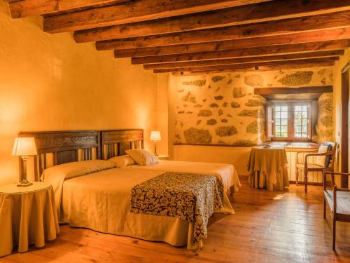 um quarto com 2 camas, uma mesa e uma janela em Posada Real La Casa de Arriba em Navarredonda de Gredos