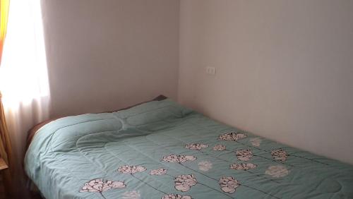 a small bedroom with a bed with a green comforter at Hostal Las Kañas in San Pedro de Atacama