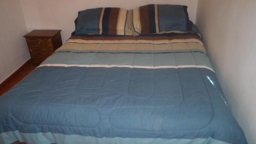 a bed in a room with a blue comforter at Hostal Las Kañas in San Pedro de Atacama