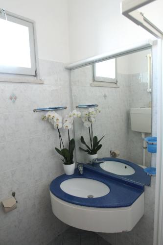 a bathroom with a blue counter with two sinks and flowers at Hotel Giorg in Rimini