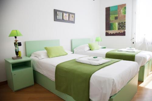 two beds in a room with green and white at B&B Botton D'Oro Basiglio in Basiglio